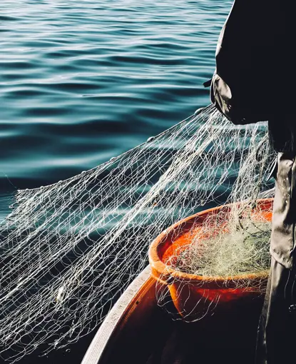 A man pulling up a fishing net from the sea