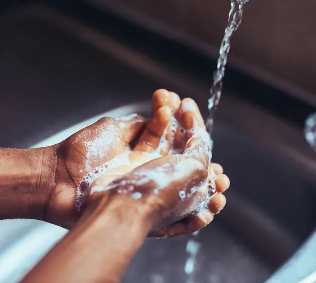 Soapy hands under tap
