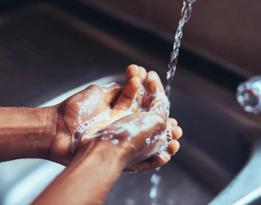 Soapy hands under tap