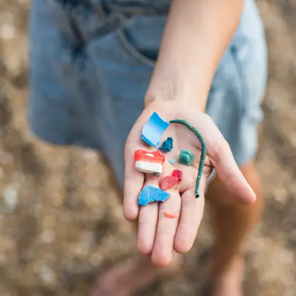Child's hand holding pieces of plastic pollution