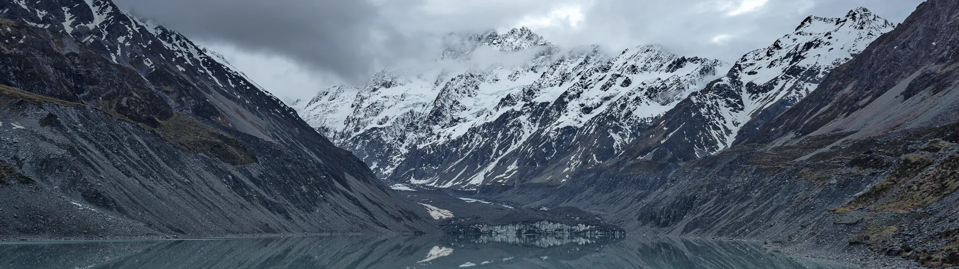 Man standing by body of water with mountains in the background